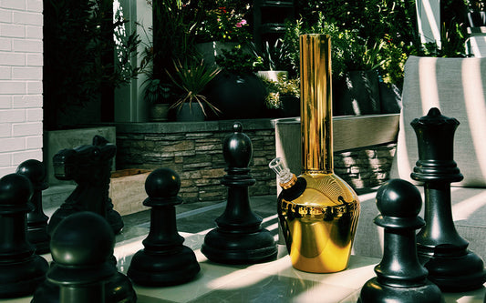 Gold bong beside black chess pieces