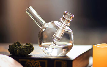 Glass water pipe with cannabis on table