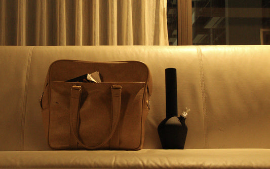 Black bong on modern yellow couch next to bag