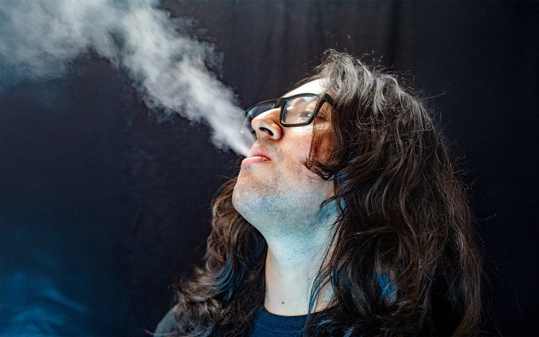 Person exhaling vapor against dark background