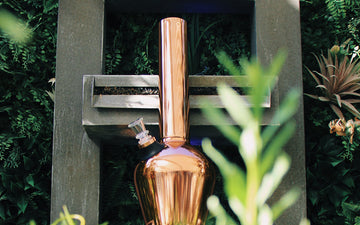 Stylish copper bong against green backdrop