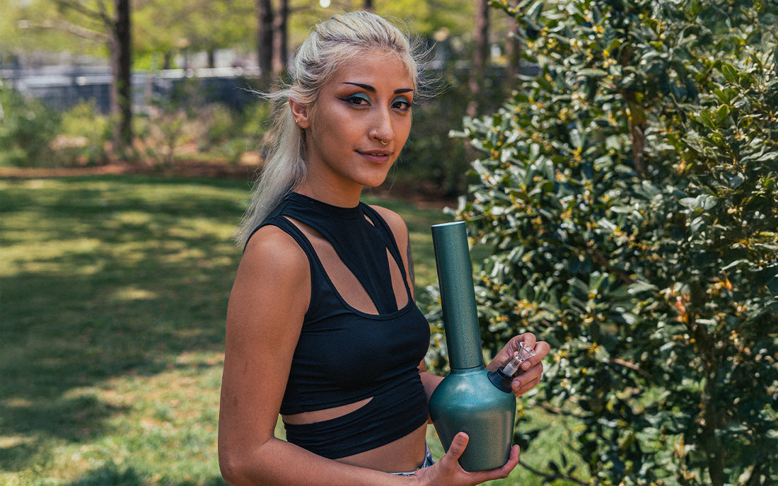 Woman holding green bong in park