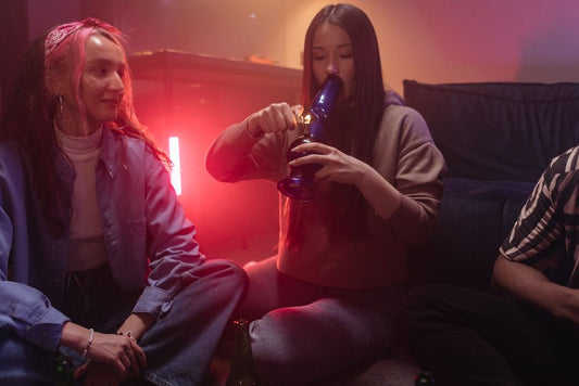 Two women sitting on floor using a bong