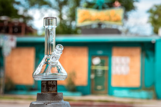 Clear glass bong in front of boarded building