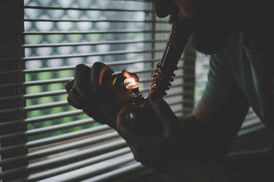Person using lighter on pipe near blinds
