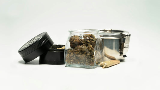 Jar of cannabis buds with grinder and joint